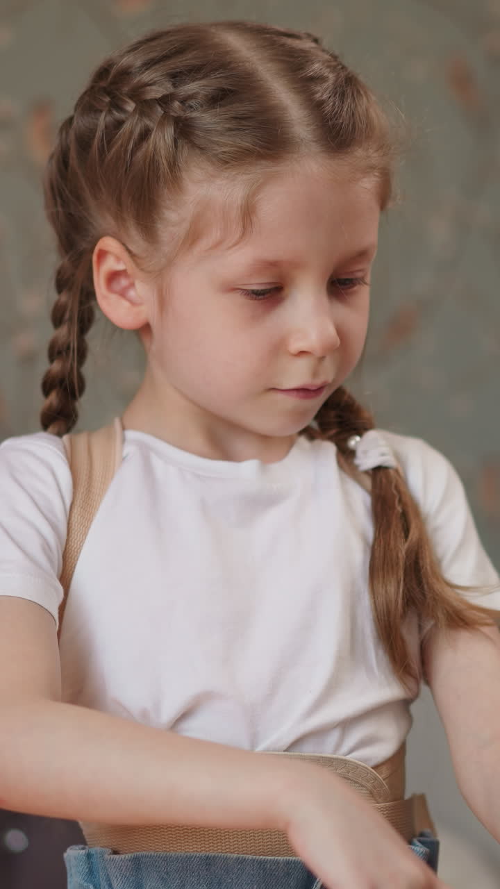 Inspired girl with long braids plays piano. Dreamy female musician wearing medical corset pauses playing and nods to beat. Serious kid studies music closeup