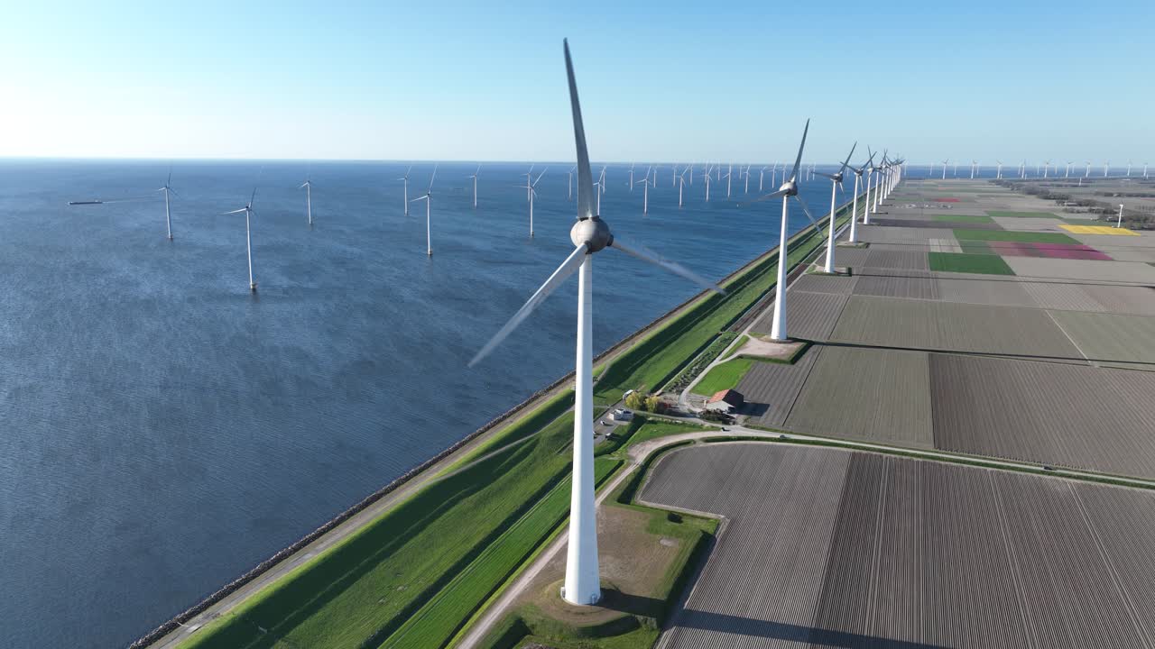 wind turbine along the water line. Renewable energy, clean energy, energy transistion. Aerial drone video.