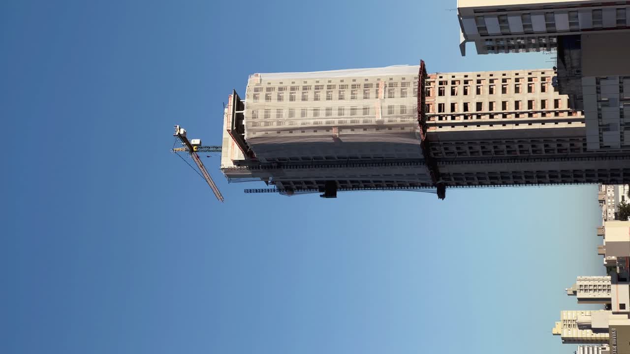 edificios, grúas de trabajo, un edificio de la ciudad está siendo hecho por dos enormes grúas blancas de construcción, un día soleado