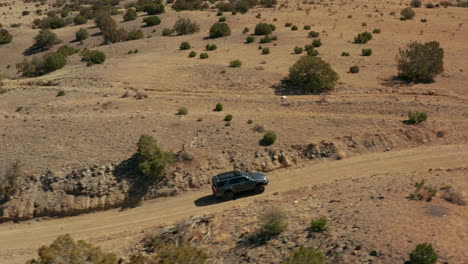 aerial tracking with adventure overland suv driving on dirt road in desert