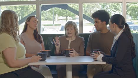 office meeting with one senior citizen woman and four younger workers with video moving out slowly