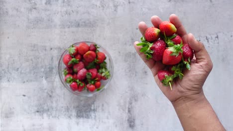 fresh strawberries in hand and bowl
