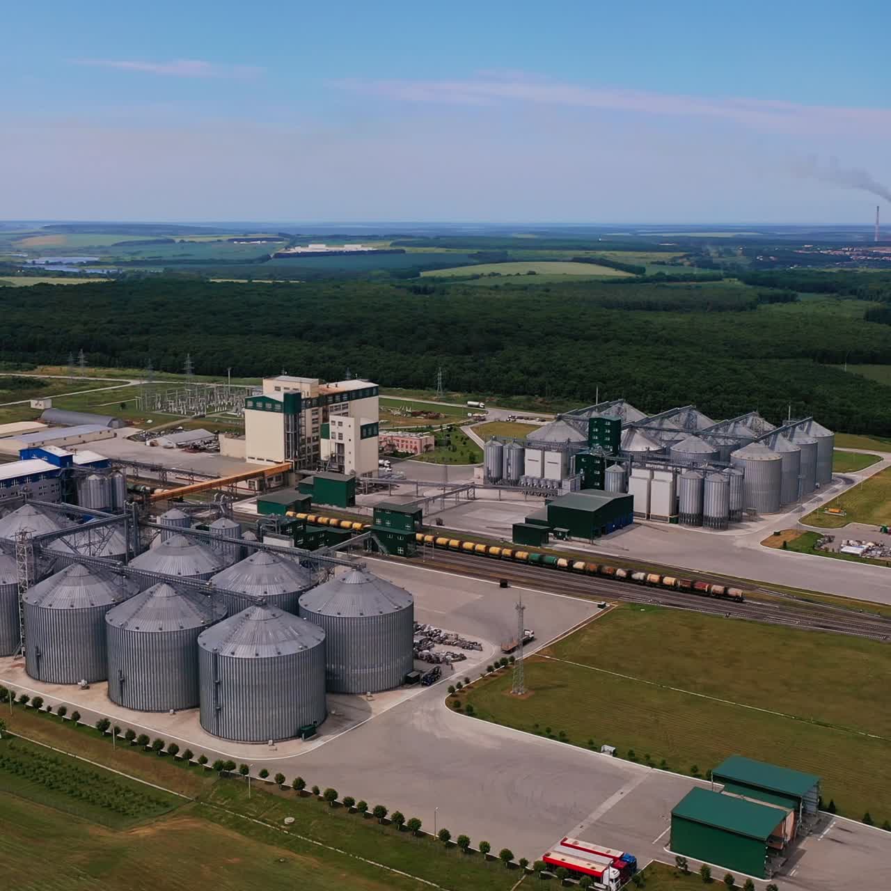 Riesige Zone für Agrarpflanzen. Agribusiness-Terminals, Metallreservoirs und Güterzüge auf dem Werksgelände. Luftaufnahme. Wälder und Ackerland im Hintergrund