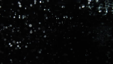 burbujas que se vierten de izquierda a derecha sobre fondo negro, efecto de agua superpuesta