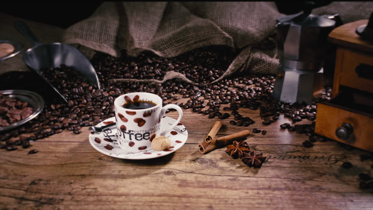 la cámara empuja hacia una taza de espresso recién vertida con canela, anís estrellado y granos de café recién tostados en una mesa de madera