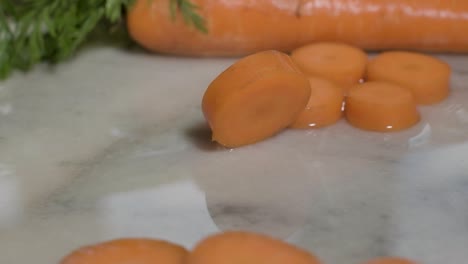 Piece-Of-Cut-Carrot-Rolling-On-Wet-Surface-In-The-Kitchen