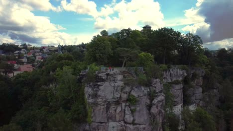 Drone-flying-closely-to-a-steep-Rockformation-with-a-few-people-standing-on-top-watching