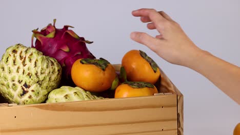 hand selecting fruit from a wooden box