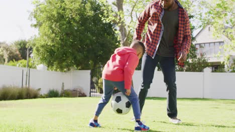 Glücklicher-Afroamerikanischer-Vater-Und-Sein-Sohn-Spielen-Fußball-Im-Garten