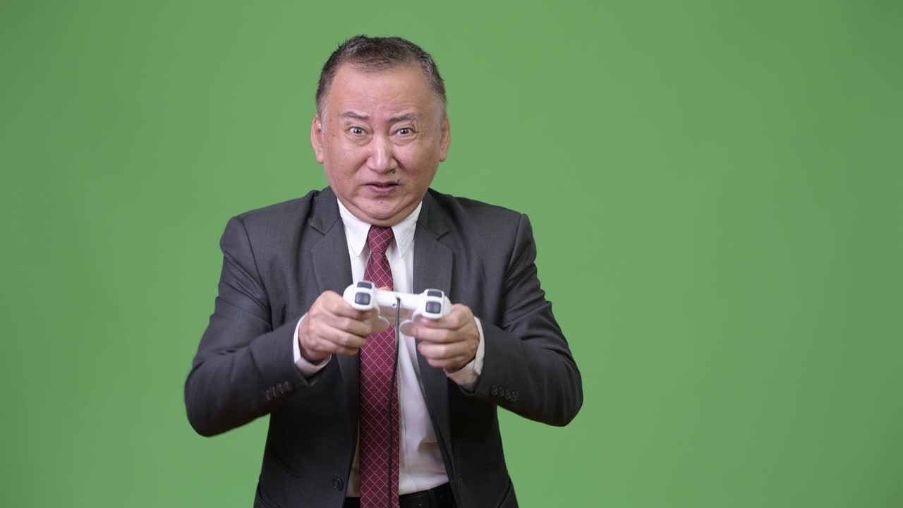 un hombre de negocios japonés maduro jugando contra un fondo verde.