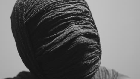 a mummy of a woman on a white backdrop rises her head