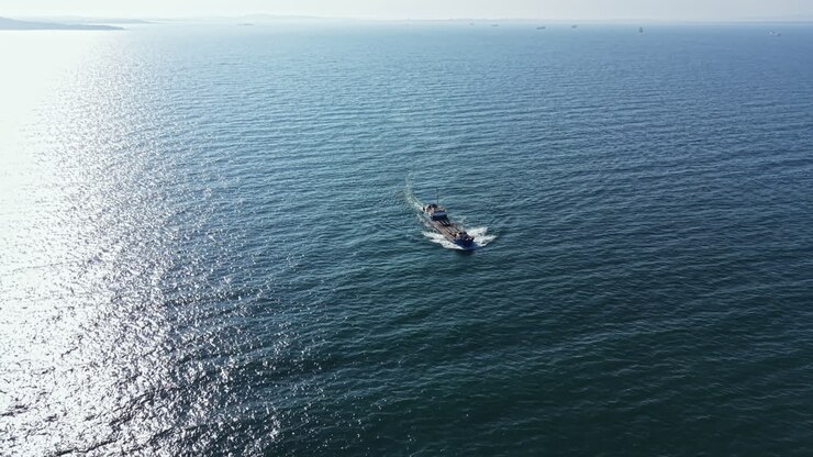 Una barca viaggia sulla superficie dell'acqua in una giornata di sole vicino alla costa con cielo sereno e mare calmo