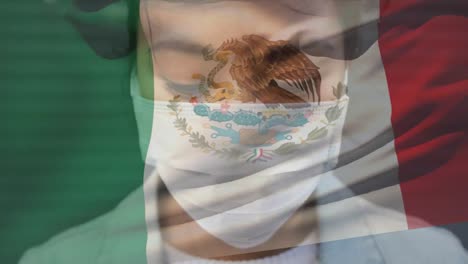 Animation-of-flag-of-mexico-waving-over-woman-wearing-face-mask-during-covid-19-pandemic