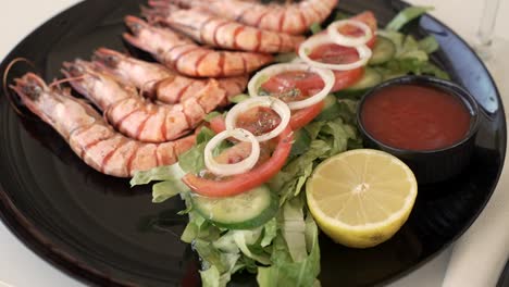 enjoying a delicious shrimp platter with fresh vegetables and zesty sauce at a sunny coastal restaurant