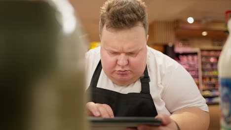 a serious and interested man does a re-inventory of goods in a supermarket. an overweight man looks with interest at the