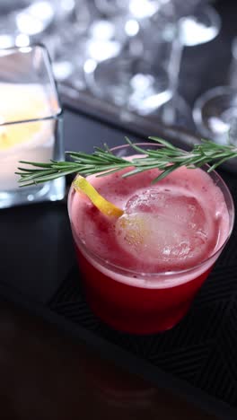 a beautiful red cocktail with rosemary and lemon