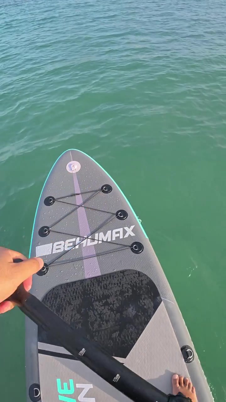 Seseorang Bermain Paddleboard di Laut Toska yang Tenang