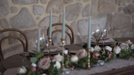 rustikaler innenhochzeitstisch mit blumigem mittelstück und hohen kerzen