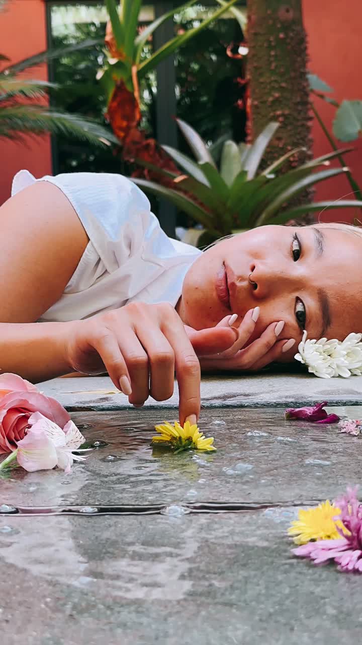 Smuk kvinde ligger i vand med blomster