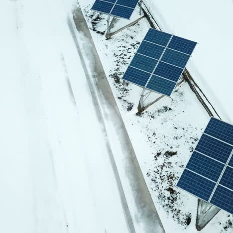 aerial solar farm low flight in winter. series of solar panels covered with snow.