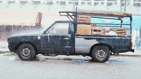 side shot of a vintage truck in slow motion, getting hit by fierce rain, illustrating the synergy of transportation and nature’s elements