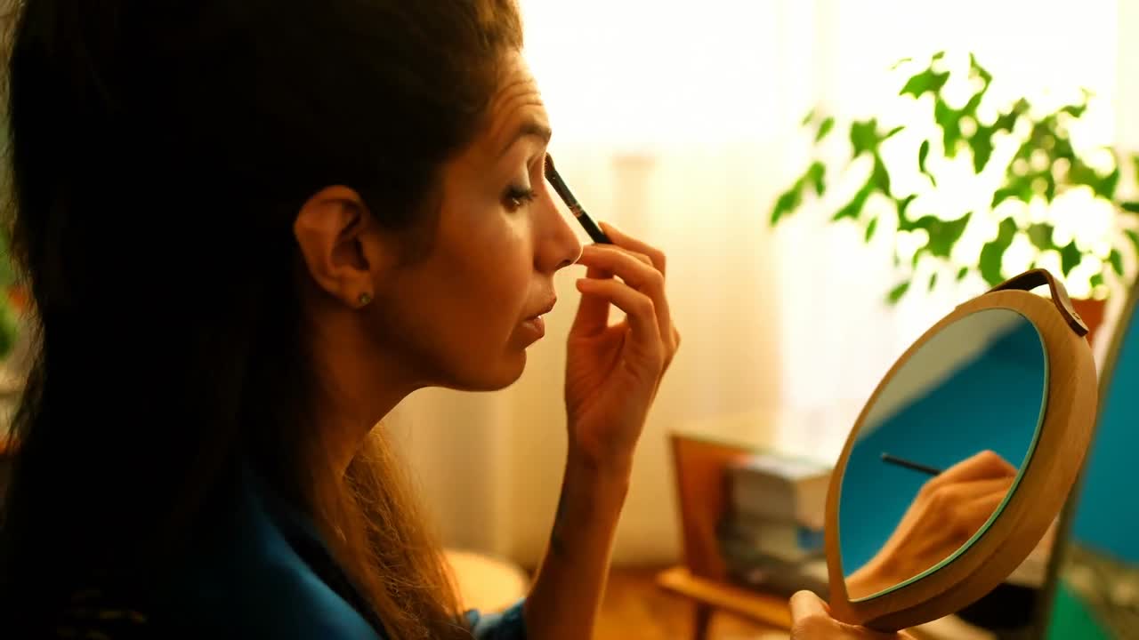 Female video blogger applying eyeshdow in front of mirror 4k