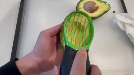 using an avocado cutter to slice an avocado into several thin pieces