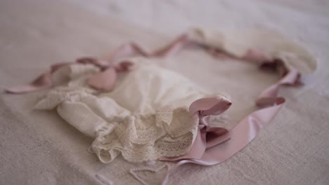 vintage baby bonnet adorned with lace and soft pink ribbons, resting on a delicate fabric, symbolizing innocence and tradition