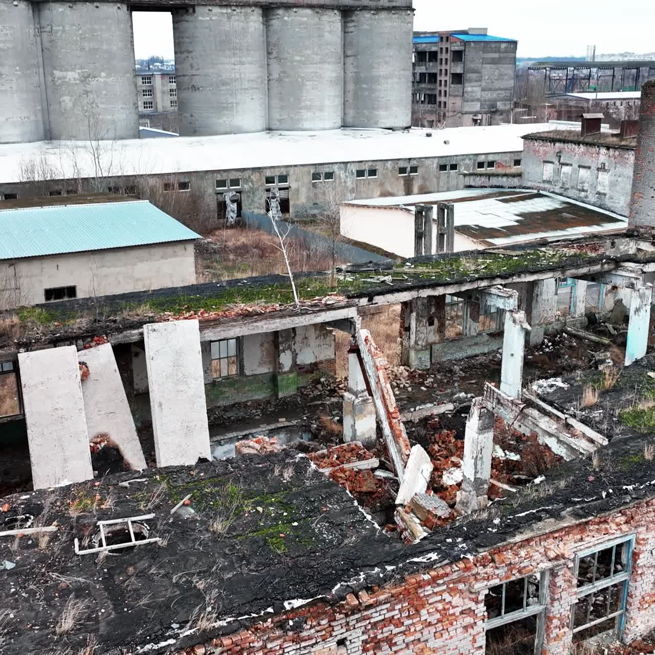 Fully ruined building with no roof or windows. Scattered bricks, beams and pieces of concrete from a premise after armed conflict. Aerial view