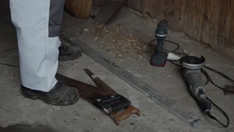 worker picks up tools from concrete floor on a farm