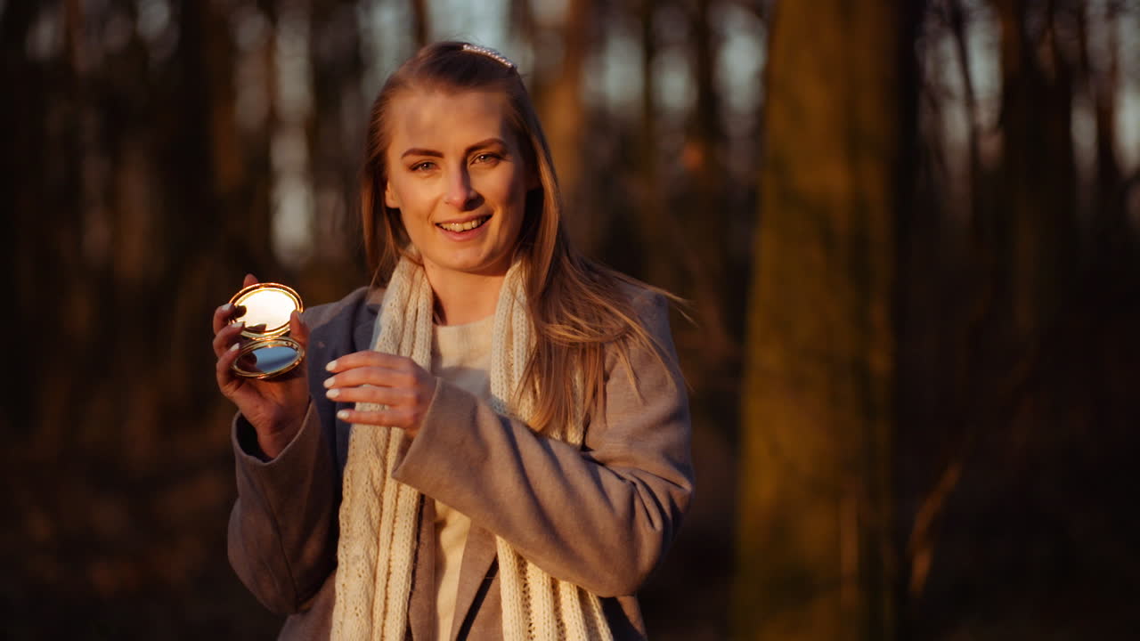 여자는 작은 거울로 빛을 반사한다