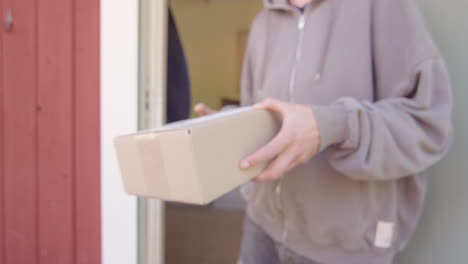 fpv view of courier guy delivering a carton package at homeowner's door