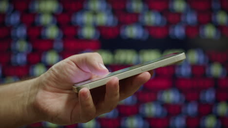 persona que utiliza un teléfono inteligente frente a un fondo de datos financieros borrosos