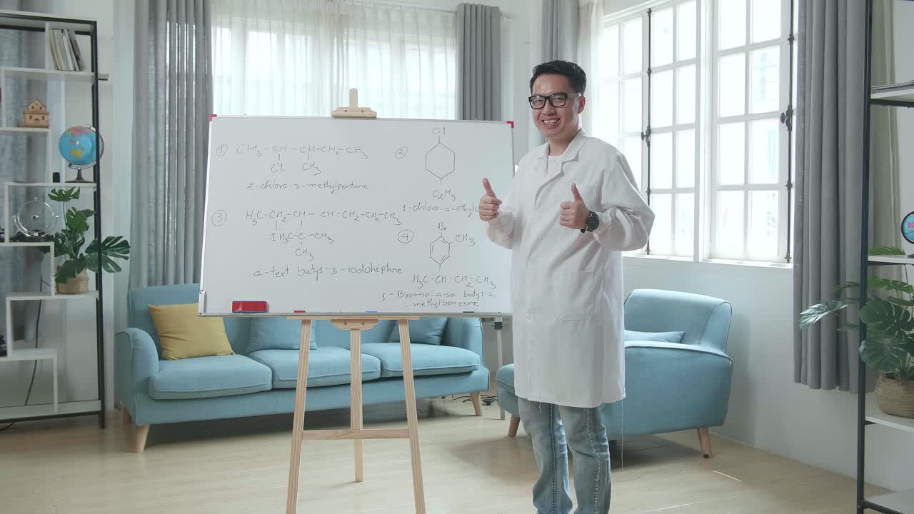 Asian Male Teacher With Glasses Showing Thumbs Up Gesture And Smiling To Camera While Teaching Chemist At Home