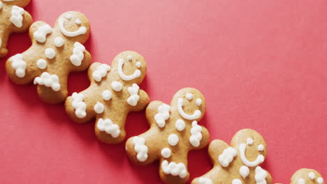 video of smiling gingerbread men with decorations over bright red background