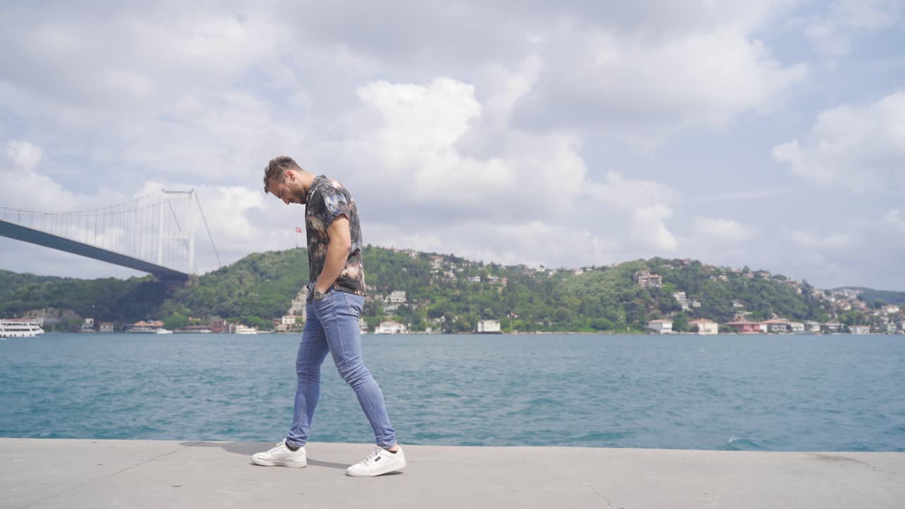 un joven aburrido y confundido está caminando por el mar.