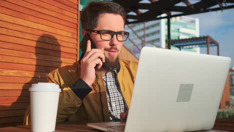 hombre trabajando en una computadora portátil al aire libre en una cafetería