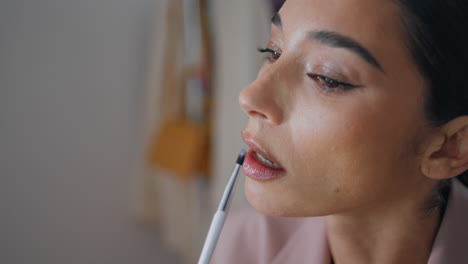 closeup model applying lipstick at home. makeup woman face drawing lips at house