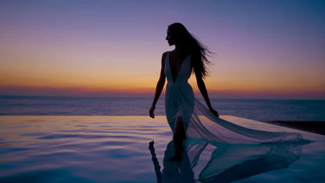 elegant woman by infinity pool at sunset