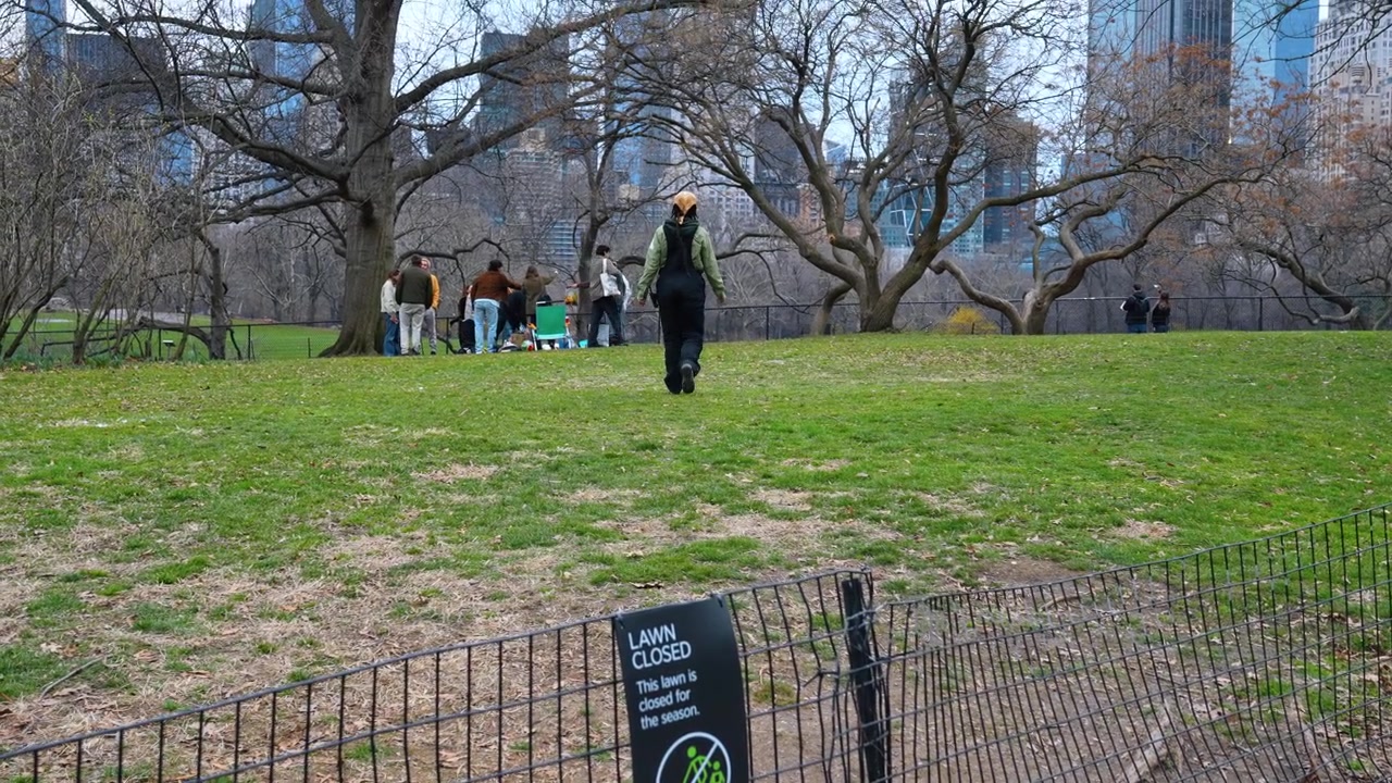 New York, USA, 25 maggio 2026: Cartello 'Prato chiuso' su una recinzione a Central Park, New York. Primo piano del cartello di avviso su una recinzione metallica, prato verde, persona che cammina dietro.