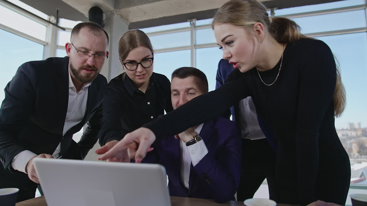 Working team gathered around laptop, look at it, discuss and smile. Colleagues building strategies and making suggestions. Office team involved in active work.
