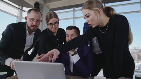 working team gathered around laptop, look at it, discuss and smile. colleagues building strategies and making suggestions. office team involved in active work.