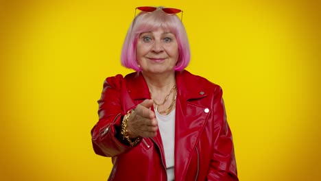 mujer mayor elegante con cabello rosa y chaqueta roja posando para una foto.