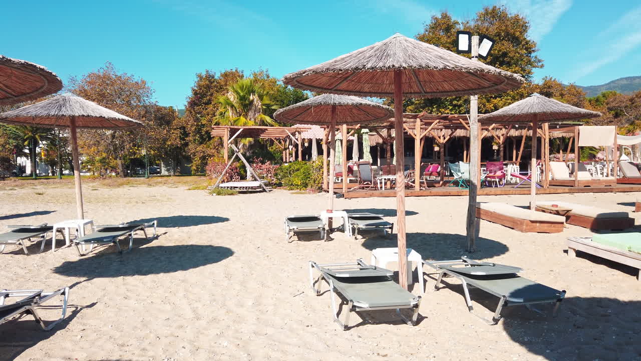 Beach on the aegean coast in Greece. Restaurant, sunbeds, umbrellas, sand