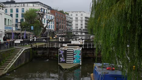 canal in camden town, weeping willow on right and tourists walking on left, london. static