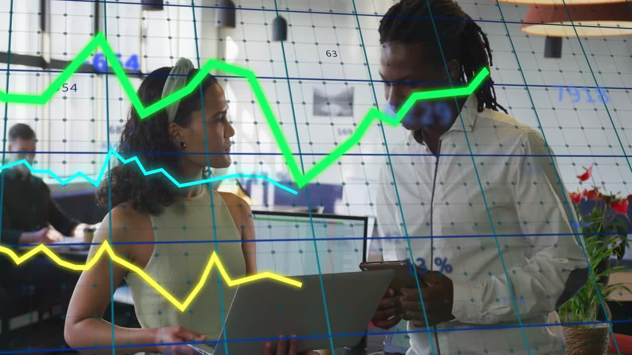 Woman tilting laptop and man tapping tablet in office, animated graphs showing business data
