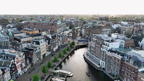 the drone is flying above the city centre going sideways looking at muntplein with the sun shining in amsterdam the netherlands aerial footage 4k