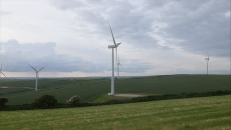 Landscape-view-of-wind-turbines-producing-green-energy-with-beautiful-cloudy-skies-background,-panning-shot