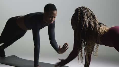 studio shot of two women wearing gym fitness clothing facing each other exercising