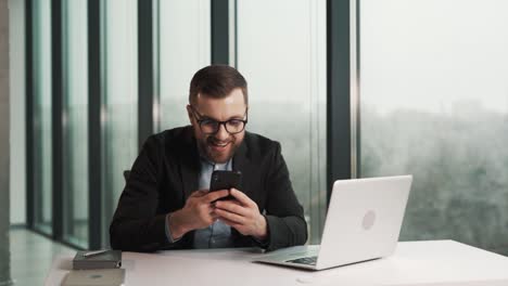 Un-Hombre-De-Negocios-Recibe-Un-Mensaje-Alegre-En-Su-Teléfono-Inteligente-Y-Está-Muy-Contento-Con-Lo-Que-Vio